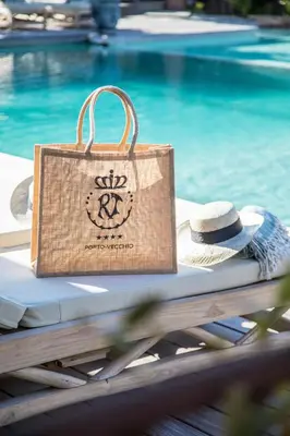 a bag sitting on a table next to a pool at Hôtel Le Roi Théodore & Spa in Porto-Vecchio