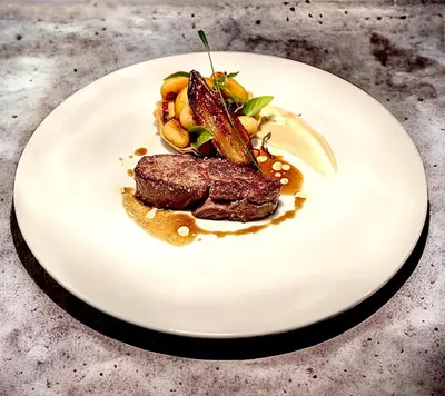 a plate with a piece of steak on a table at Hôtel Le Roi Théodore & Spa in Porto-Vecchio