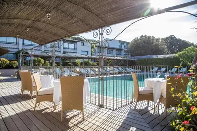 a patio with tables and chairs next to a pool at Hôtel Le Roi Théodore & Spa in Porto-Vecchio