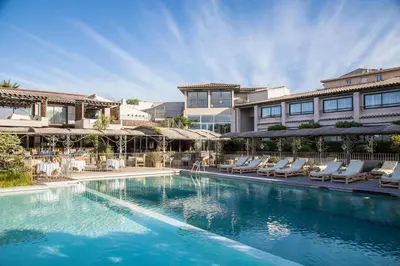 a swimming pool with lounge chairs and a building at Hôtel Le Roi Théodore & Spa in Porto-Vecchio