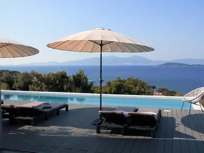 a pool with two umbrellas and chairs next to a swimming pool at Dililodge in Verghia