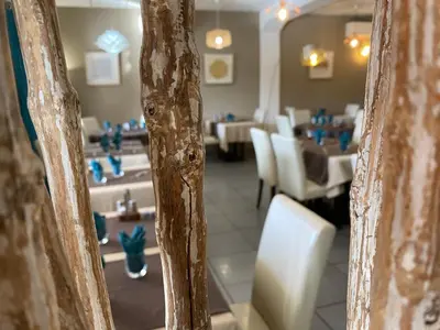 a room with a bed and a table with a lamp at Hôtel Restaurant L' Empereur in Aléria