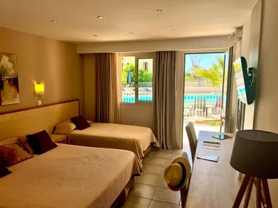 a hotel room with two beds and a balcony at Hôtel Restaurant L' Empereur in Aléria