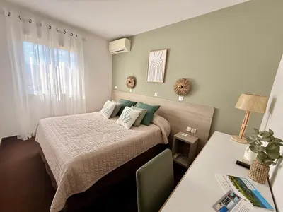 a bedroom with a bed with two green pillows at Hôtel Restaurant L' Empereur in Aléria