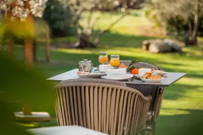 a table with a plate of food and glasses of orange juice at Hôtel Spa Restaurant La Madrague in Lucciana