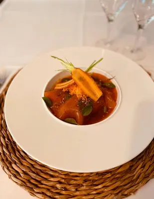 a bowl of soup on a white plate on a table at Hôtel Spa Restaurant La Madrague in Lucciana