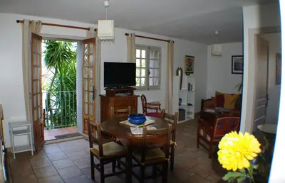 a living room with a table and a television at GITE , Maison de vacances avec extérieur et terrasse fleurie meublé tourisme 3 étoiles in Poggio-di-Tallano