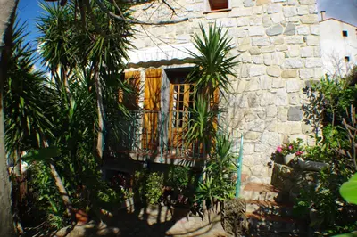 a stone building with a balcony and palm trees at GITE , Maison de vacances avec extérieur et terrasse fleurie meublé tourisme 3 étoiles in Poggio-di-Tallano