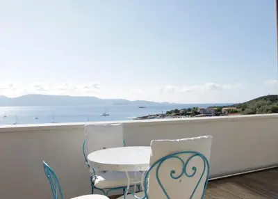 a balcony with a table and chairs and a view of the ocean at Les jardins de Porto Pollo in Porto Pollo
