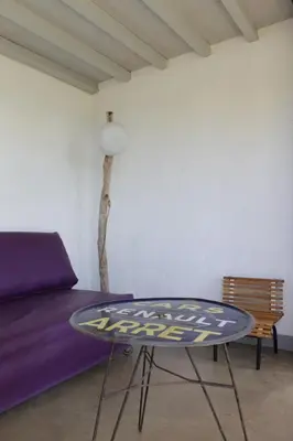 a table and a bed in a room with a purple couch at Les jardins de Porto Pollo in Porto Pollo
