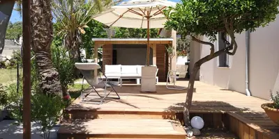 a wooden deck with an umbrella and a chair at Les jardins de Porto Pollo in Porto Pollo