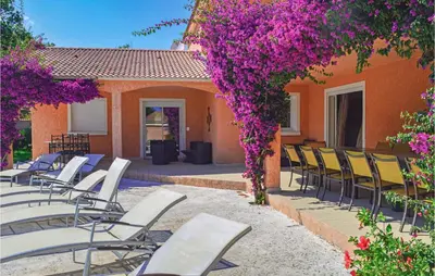 a group of chairs and purple flowers on a patio at Cozy Home In Moriani Plage With Wifi in Moriani Plage