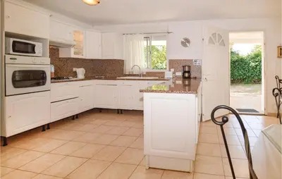 a kitchen with white cabinets and a tile floor at 3 Bedroom Nice Home In Moriani Plage in Moriani Plage