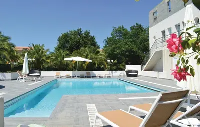 a swimming pool with chairs and a building at 3 Bedroom Nice Home In Moriani Plage in Moriani Plage