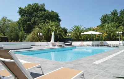a swimming pool with chairs and umbrellas in a resort at 3 Bedroom Nice Home In Moriani Plage in Moriani Plage