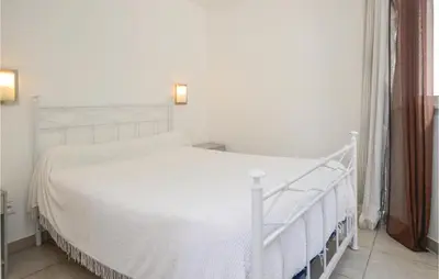 a white bed in a bedroom with a white bed frame at Nice Apartment In Moriani Plage in Moriani Plage