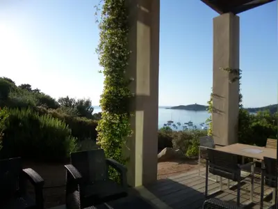 a living room with couches and a table and large windows at Villa Libecciu in Sainte-Lucie de Porto-Vecchio