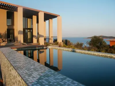 a house with a swimming pool in front of the ocean at Villa Libecciu in Sainte-Lucie de Porto-Vecchio