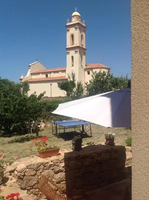 a white building with a clock tower in the background at A Stalla in Piana