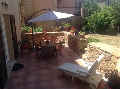 a patio with a table and chairs and an umbrella at A Stalla in Piana