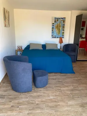 a bedroom with a blue bed and two chairs at A Stalla in Piana