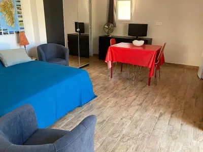 a room with a red table and chairs and a television at A Stalla in Piana