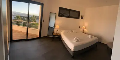 a bedroom with a large bed and a balcony at Résidence Les Jardins du Fort in Porticcio