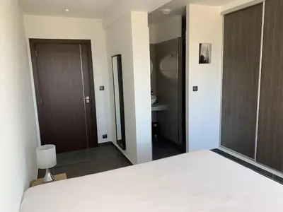 a bedroom with a white bed and a bathroom at Résidence Les Jardins du Fort in Porticcio