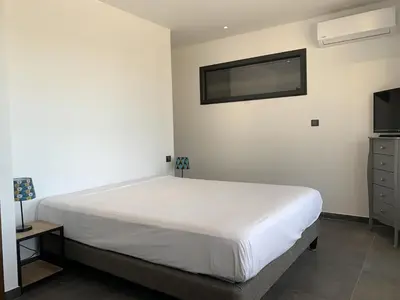 a bedroom with a bed and a tv on the wall at Résidence Les Jardins du Fort in Porticcio