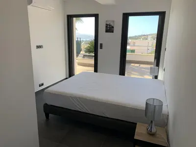 a bedroom with a bed and a large window at Résidence Les Jardins du Fort in Porticcio