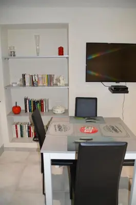 a dining room table with chairs and a television at maison corse en balagne in Cateri