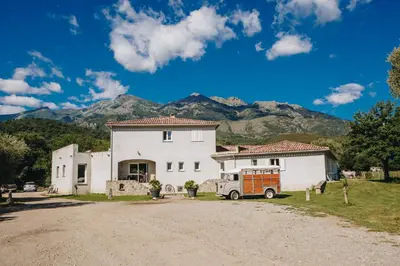 a white house with a car parked in front of it at B&B A Chjusellina in Corte