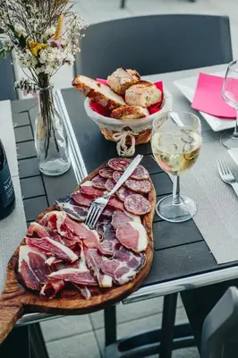 a table with a plate of meat and a glass of wine at B&B A Chjusellina in Corte