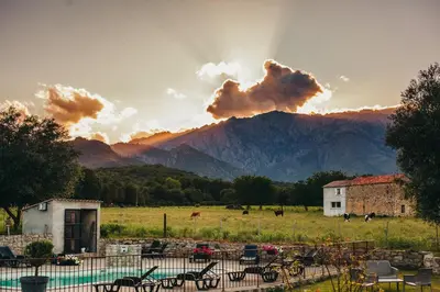 a sunset over a field with a mountain in the background at B&B A Chjusellina in Corte