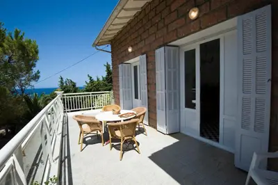 a patio with a table and chairs on a balcony at Villa Kalliste in Porto Ota