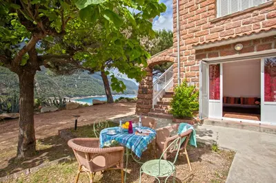 a patio with a table and chairs and a tree at Villa Kalliste in Porto Ota