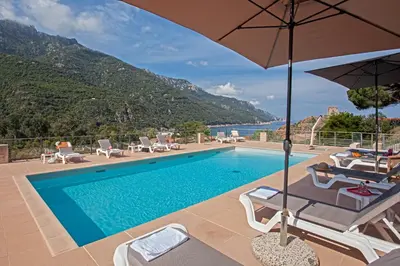 a swimming pool with chairs and an umbrella at Villa Kalliste in Porto Ota