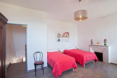 a bedroom with two beds with red covers and a fireplace at Gîte Du Pont - Piana in Piana