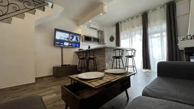 a living room with a table and a kitchen with a tv at Appartement Maenat in Borgo