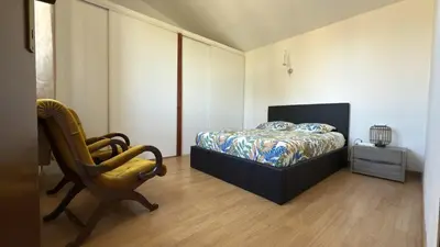 a bedroom with a bed and a chair at Appartement Maenat in Borgo