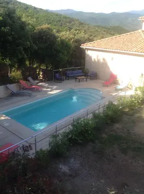 a swimming pool with chairs and a house at Apartement Alba Oletta in Oletta