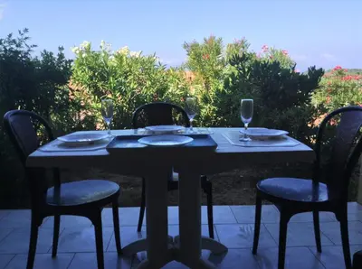 a table with chairs and wine glasses on a patio at Panoramic Seaview studio Tiuccia in Casaglione