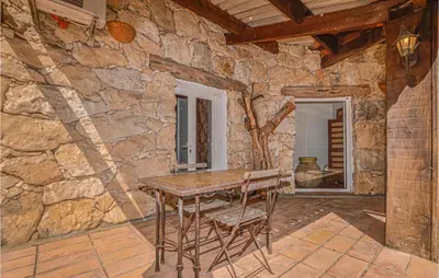 a stone room with a wooden table and chairs at Gorgeous Home In Figari in Figari