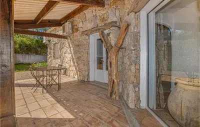 a patio with a table and a stone wall at Gorgeous Home In Figari in Figari