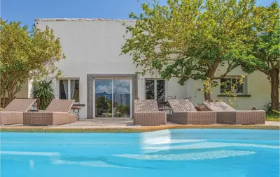 a group of wicker chairs sitting next to a pool at Gorgeous Home In Figari in Figari