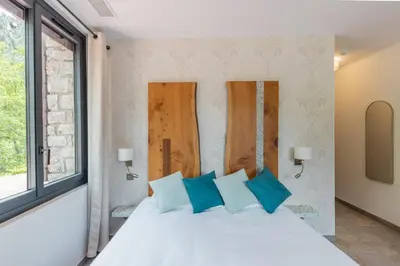 a bedroom with a white bed with blue pillows at Hôtel de la Restonica in Corte