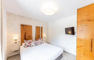 a bedroom with a white bed with pillows on it at Hôtel de la Restonica in Corte