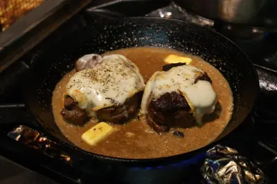 a pan filled with soup with meatballs and cheese at Hôtel de la Restonica in Corte