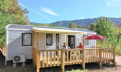 two people sitting on the porch of a tiny house at Camping Corsica Paradise in Calcatoggio