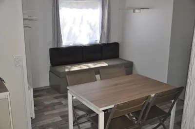 a dining room with a table and a couch at Camping Corsica Paradise in Calcatoggio